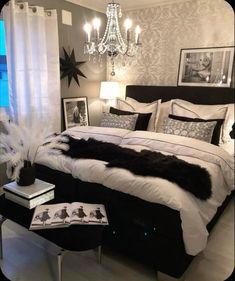 a black and white bedroom with chandelier, bedding, pillows and pictures on the wall