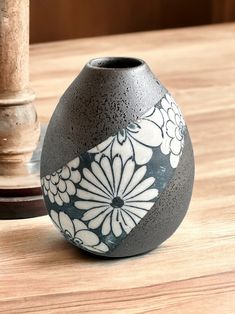 a black and white vase sitting on top of a table next to a candle holder