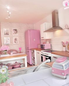 a kitchen with pink appliances and pictures on the wall