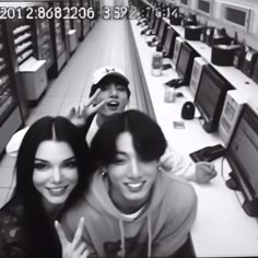 three people are posing for a photo in front of computers