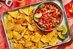 a tray filled with chips and salsa on top of a table next to two glasses