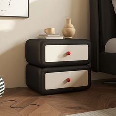 two black and white drawers with red knobs next to a bed in a bedroom