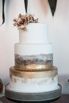 a white and gold wedding cake with flowers on top