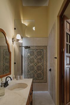 a bathroom with a sink, mirror and shower stall is pictured in this image from the inside