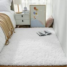 a bed with a white fluffy rug on top of it next to a night stand