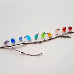 a group of birds sitting on top of a tree branch with colored glass beaks