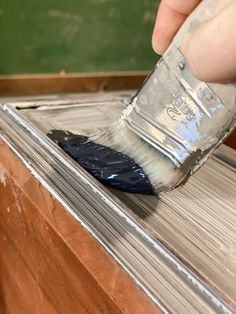 a person using a brush to paint the side of a wooden box with metal foil