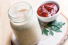 there is a jar of sauce next to a small bowl of food on a plate