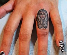 a woman's hand with an egyptian tattoo on her left thumb and the middle finger