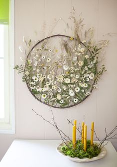 a white table topped with a plate filled with flowers and candles next to a mirror