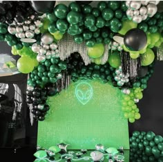 a table topped with lots of green and white balloons