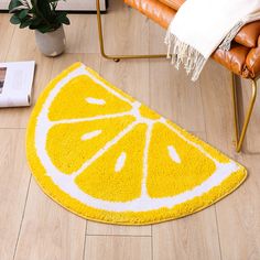 a yellow and white rug on the floor with a slice of lemon in front of it