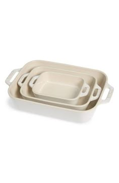 three white dishes with handles on each side and one empty dish in the middle,