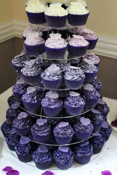 a tiered cake with purple cupcakes on it