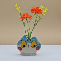 a blue and white cat vase with orange flowers in it