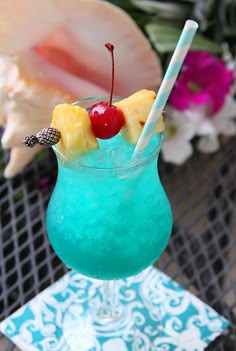 a blue drink with pineapple and cherries in it