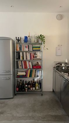 a refrigerator freezer sitting next to a metal shelf filled with books