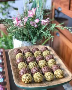 there are many cookies on the table with flowers in the vase behind it and another plate full of them