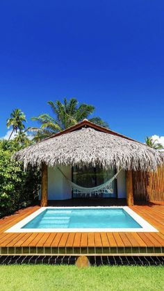 a small pool with a thatched roof next to a wooden deck