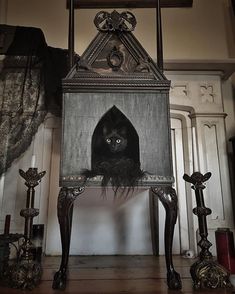 a black cat sitting on top of a wooden table in front of a cross and candles