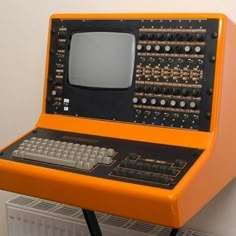 an orange computer sitting on top of a radiator next to a white wall