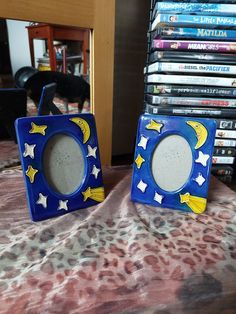 two small blue and yellow frames sitting on top of a bed