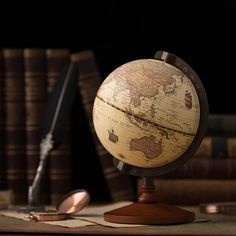 an old world globe sits on a desk next to some books and a quill