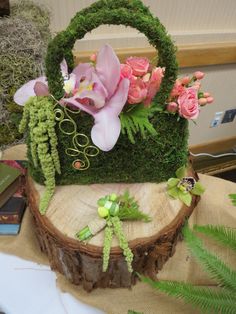 an arrangement of flowers in a basket on top of a tree stump