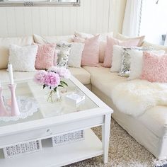 a living room filled with white furniture and pink pillows