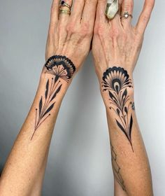 two women with matching tattoos on their arms holding hands up to each other's palms