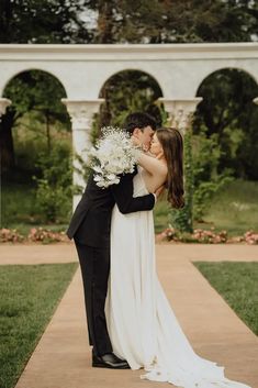 a bride and groom kissing in front of an archway