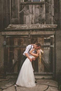 a bride and groom kissing in front of an old building with the words happily eat kiss kiss written on it