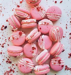 pink macaroons with white frosting and red sprinkles