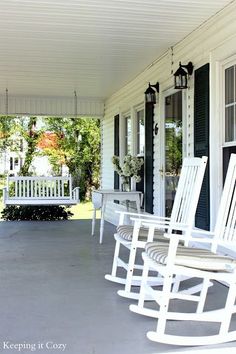 three white rocking chairs sitting on the front porch