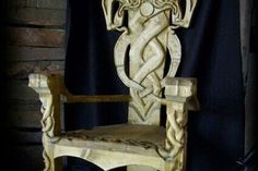 a carved wooden chair sitting in front of a black curtain with an intricate design on it