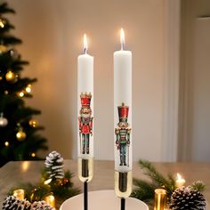 two candles are sitting on a plate with christmas decorations