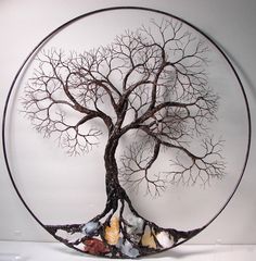 a metal tree sculpture sitting on top of a white table next to a glass plate