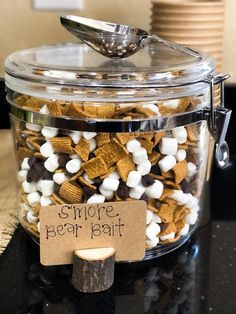 a glass jar filled with marshmallows and other snacks on top of a table