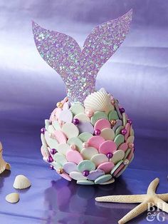 a cake decorated like a mermaid tail with seashells and starfish on the table