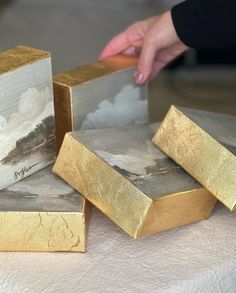 three gold bars sitting on top of a table next to a person's hand