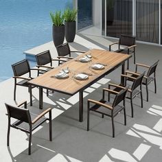 an outdoor dining table with six chairs next to a pool