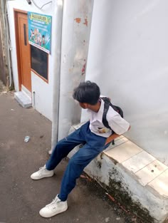 a young man sitting on a bench in front of a building with his back to the camera