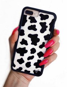 a woman's hand holding an iphone case with black and white cow print