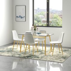 a dining room table with white chairs and a rug on the floor in front of it