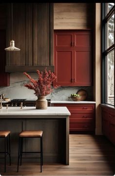 a kitchen with red cabinets and white counter tops, two stools are in front of the island