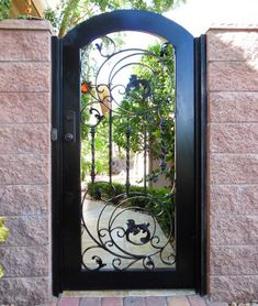 a wrought iron door is shown in front of a pink brick wall and stone walkway