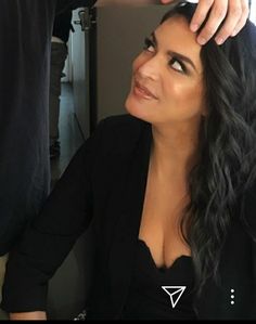 a woman getting her hair styled by a man in a black shirt and blazer