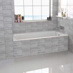 a bathroom with white tile walls and flooring next to a window overlooking the ocean