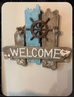 a wooden sign that says welcome with a ship wheel on it and seashells