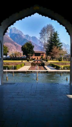 an archway leading into a garden with mountains in the background